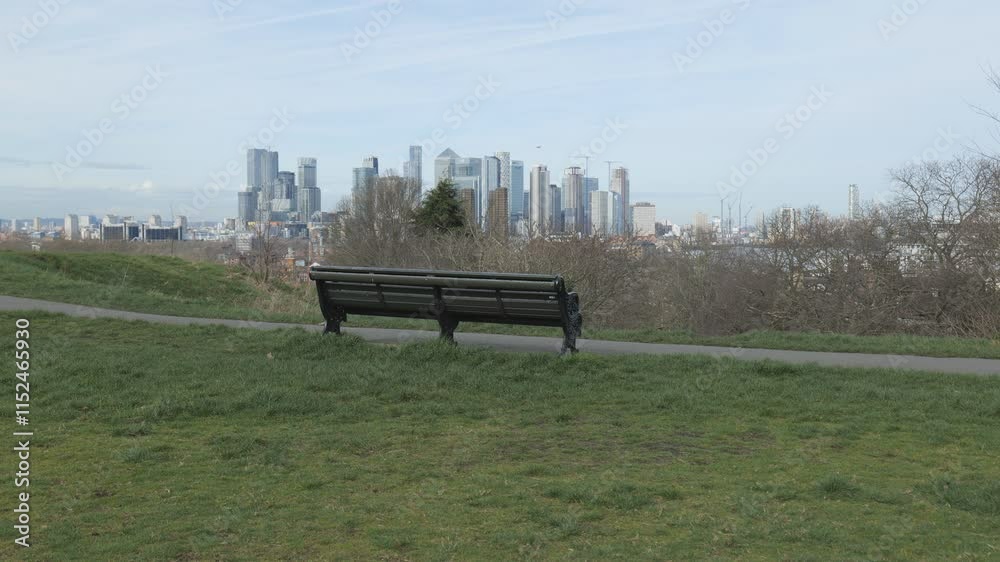 A park bench overlooking a modern city skyline.