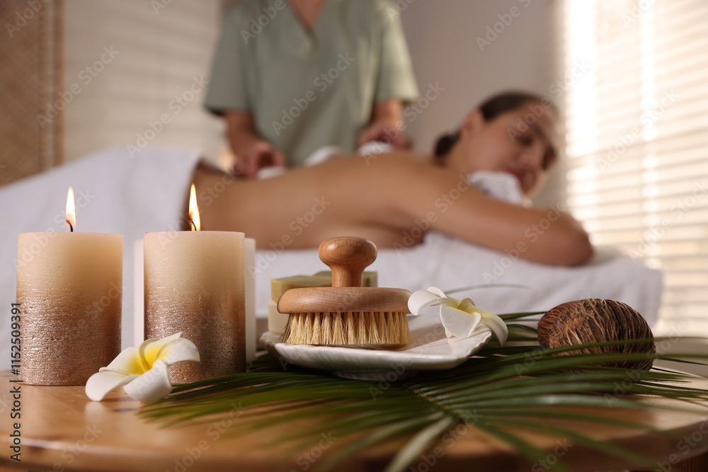 Woman receiving hot stone massage in salon, focus on spa supplies Woman receiving hot stone massage in salon, focus on spa supplies