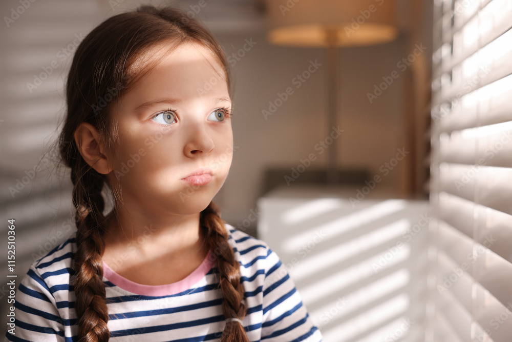 Orphanage concept. Sad girl and looking through window blinds indoors Orphanage concept. Sad girl and looking through window blinds indoors