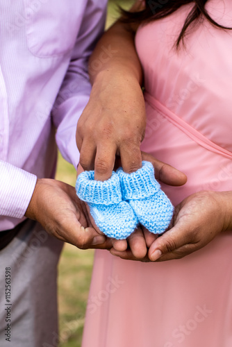 pregnant couple holding baby's slippers