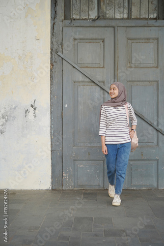 asian muslim woman standing in front of old big wooden door