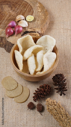 Traditional Indonesian kerupuk snacks, made from catfish, served in a wooden place on a white table with a studio lighting