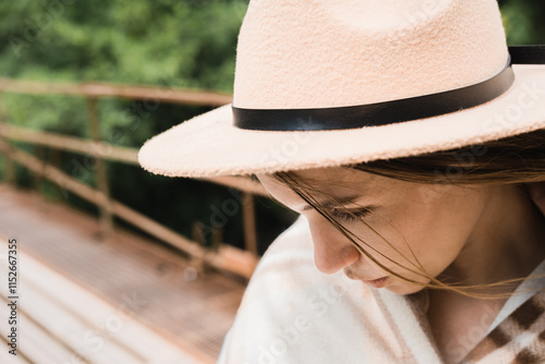 Young woman wearing a hat outdoors with a thoughtful expression in sunlight