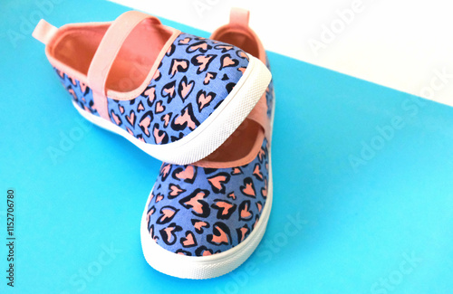 Multi colored canvas shoes with hearts pattern, white blue background photo