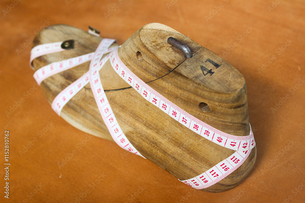 shoe last and measuring tape wrapped around them isolated on brown leather sheet background shoe last and measuring tape wrapped around them isolated on brown leather sheet background
