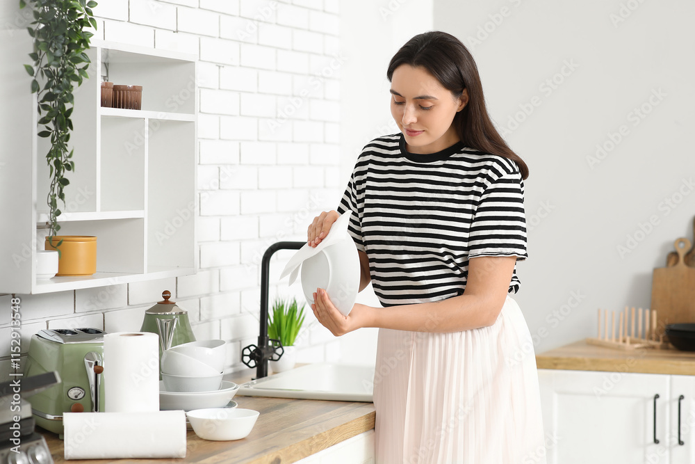 Beautiful young happy woman wiping plates with paper towels in kitchen Beautiful young happy woman wiping plates with paper towels in kitchen