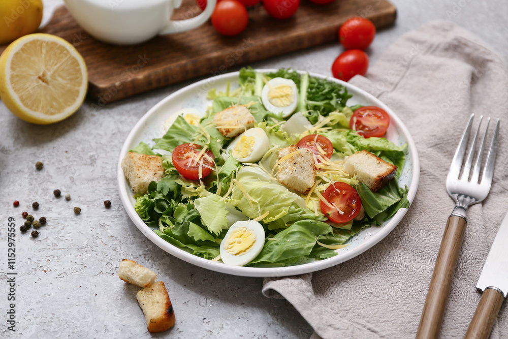 Plate with tasty Caesar salad, lemon and peppercorn on grey background Plate with tasty Caesar salad, lemon and peppercorn on grey background