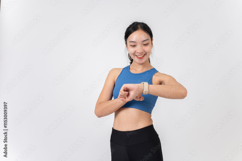 A smiling Asian woman in sportswear checking her workout calories burned on her smartwatch. A smiling Asian woman in sportswear checking her workout calories burned on her smartwatch.