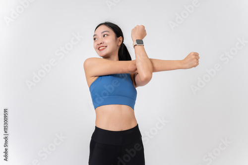 A beautiful, healthy Asian woman in sportswear stretching her arms and body, studio background.