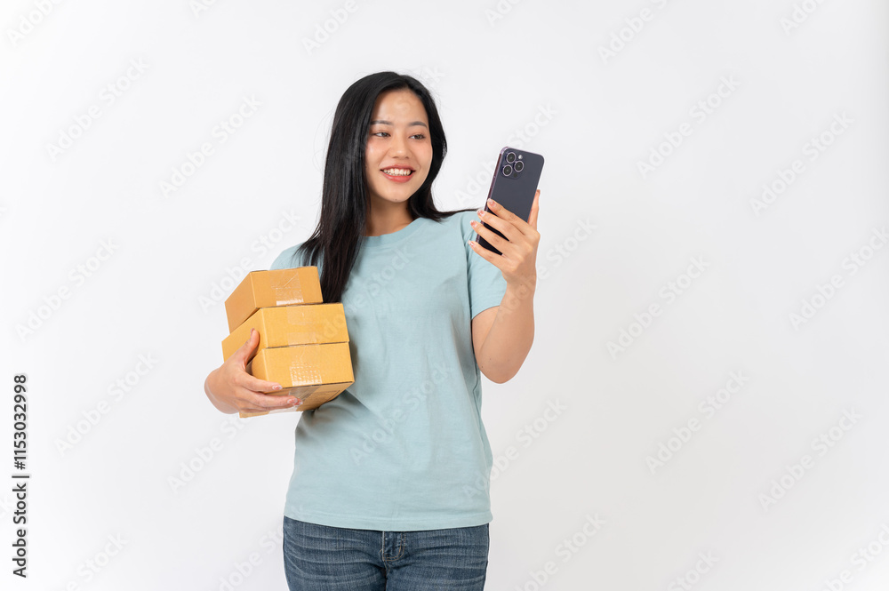 A smiling woman standing against a white studio background, holding cardboard boxes and a smartphone A smiling woman standing against a white studio background, holding cardboard boxes and a smartphone
