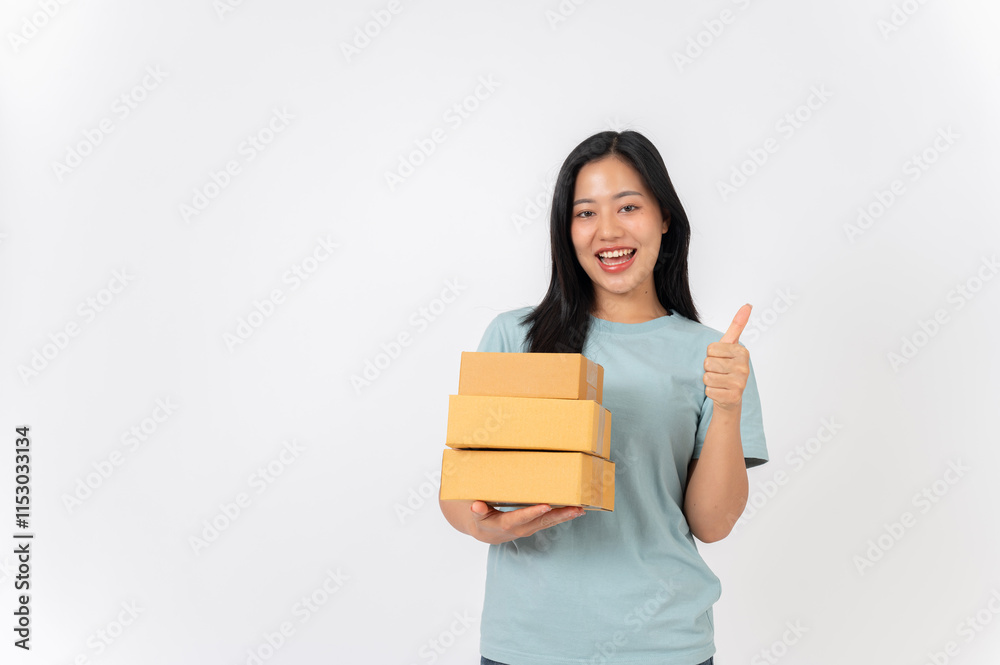 A cheerful Asian woman standing against a white studio background, holding cardboard boxes. A cheerful Asian woman standing against a white studio background, holding cardboard boxes.