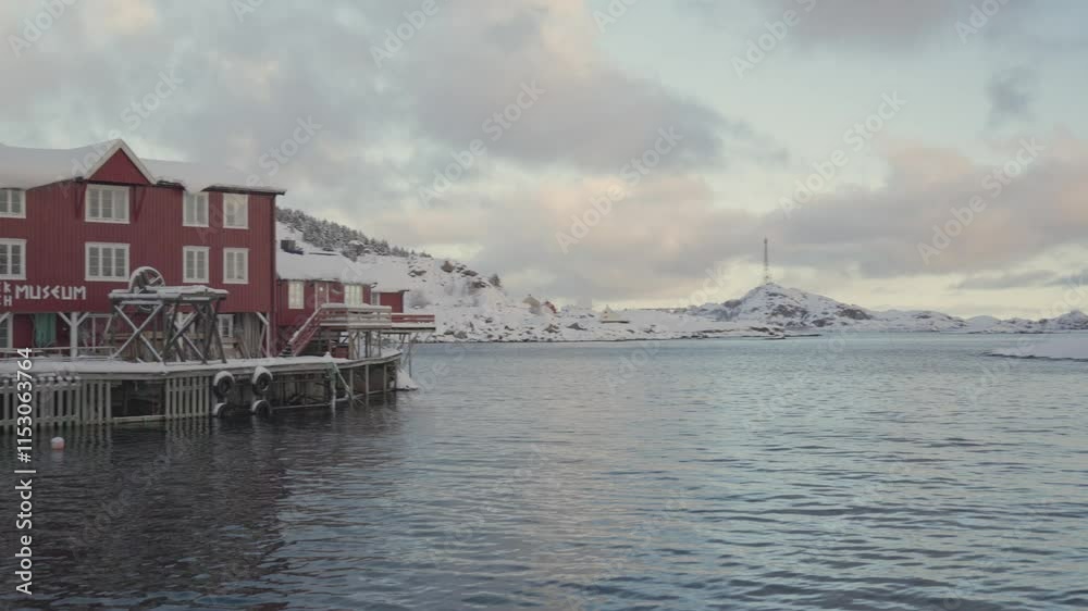 Fishing museum in Reine Lofoten Norway at winter morning with panning view over the fjord and snow covered mountains Fishing museum in Reine Lofoten Norway at winter morning with panning view over the fjord and snow covered mountains