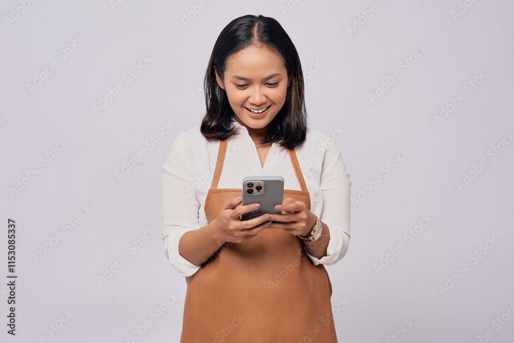 Smiling young Asian woman barista barman employee wearing brown apron working in coffee shop using mobile phone isolated on white background. Small business startup concept Smiling young Asian woman barista barman employee wearing brown apron working in coffee shop using mobile phone isolated on white background. Small business startup concept