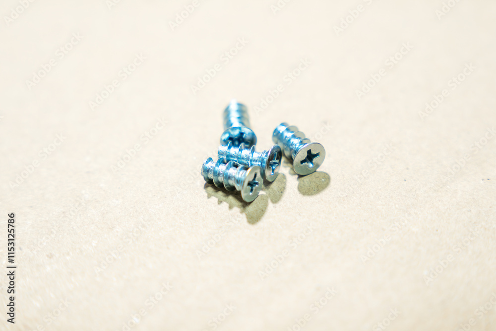 Metal screws for furniture assembly lie on a cardboard surface. Furniture screws close-up. Metal screws for furniture assembly lie on a cardboard surface. Furniture screws close-up.