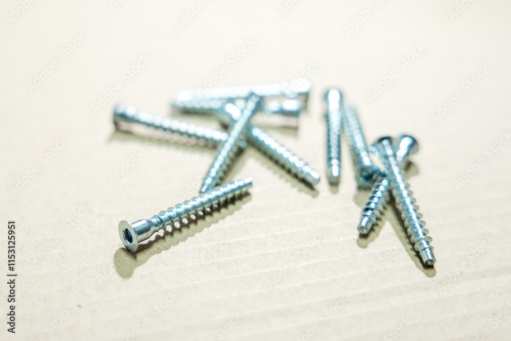 Metal screws for furniture assembly lie on a cardboard surface. Furniture screws close-up. Metal screws for furniture assembly lie on a cardboard surface. Furniture screws close-up.