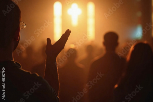 A religious man holding his hands up in worship as people in a church congregation sings hymns and songs in praise of God. Christian worshippers during Christmas vigil, Good Friday, Easter Sunday.