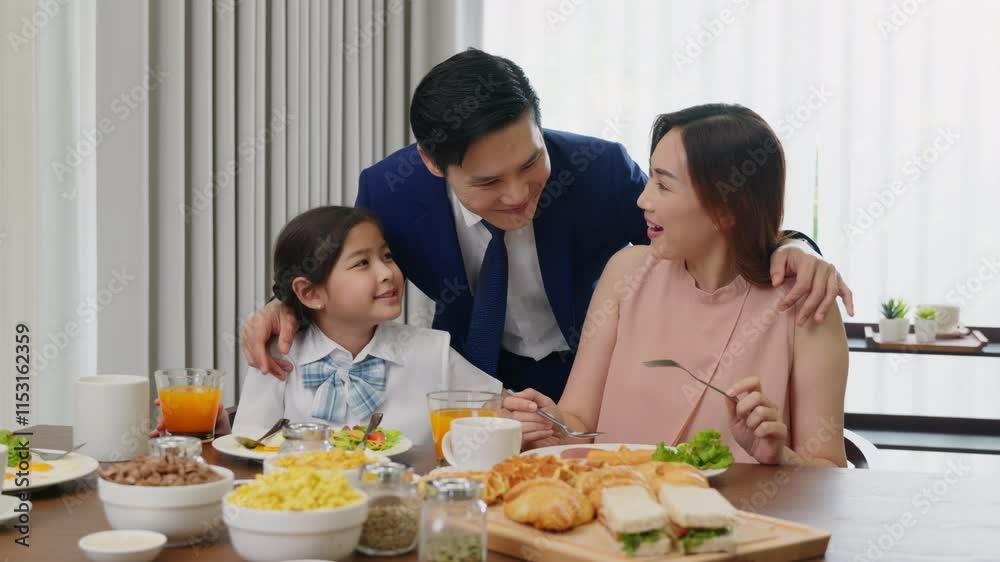 Happy Asian family enjoying a meal together at a table, father wearing a suit, mother and daughter having breakfast in morning at home, Parents laughing with their children, support and healthy meal
