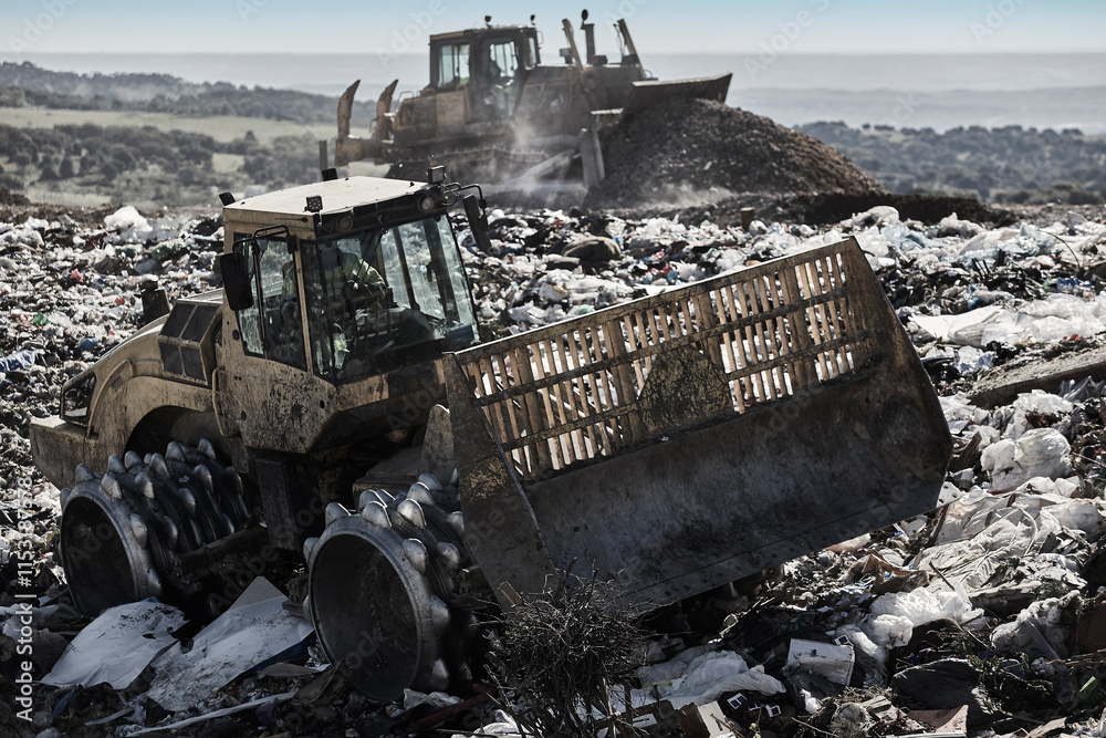 Heavy machinery shredding garbage in an open air landfill. Pollution