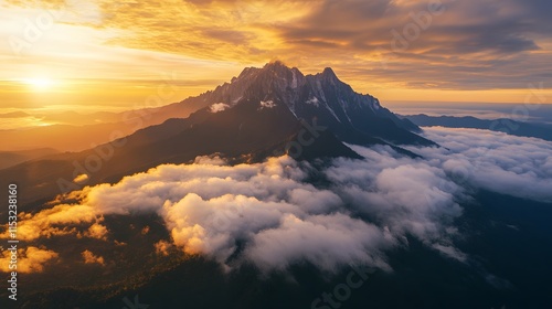 Aerial shot of Mount Kinabalu glowing under the golden sunrise, with its rugged peaks surrounded by dense clouds, in 4K resolution