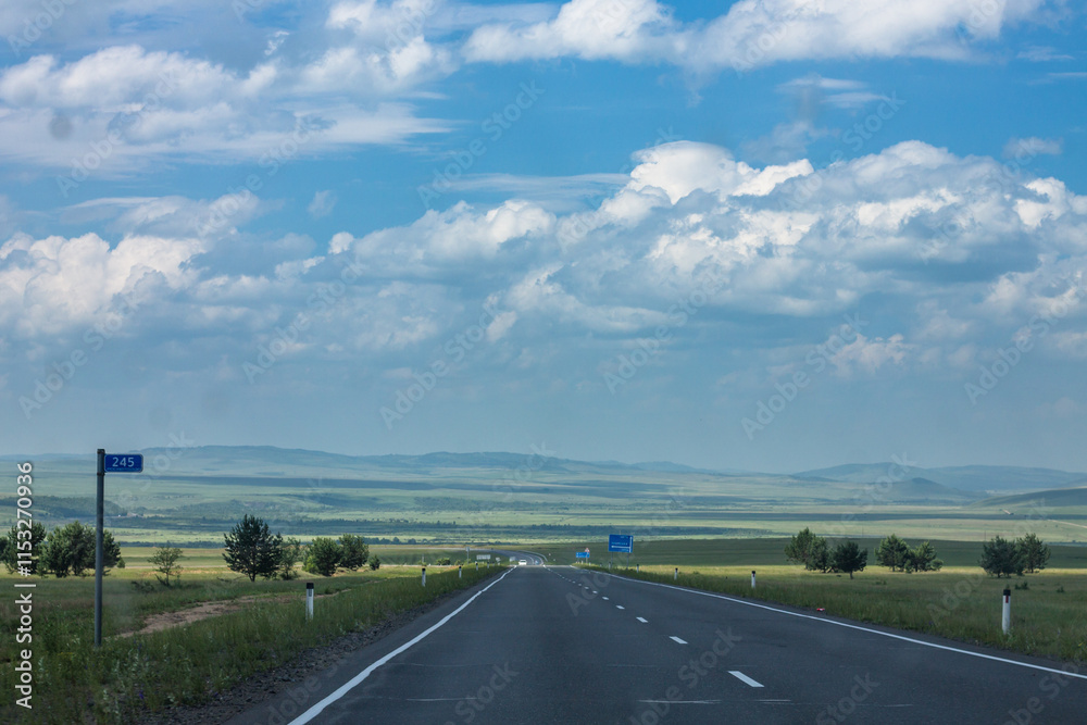Asphalt road in the steppe against the blue sky with clouds Asphalt road in the steppe against the blue sky with clouds