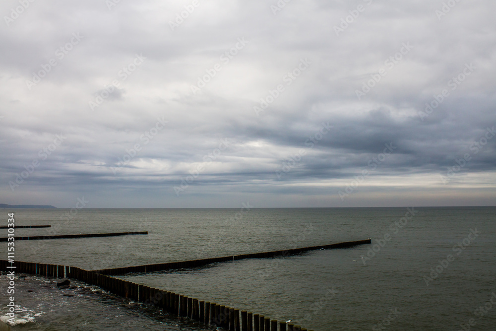 Dramatic cloudy sky over the sea with wooden breakwaters. Dramatic cloudy sky over the sea with wooden breakwaters.