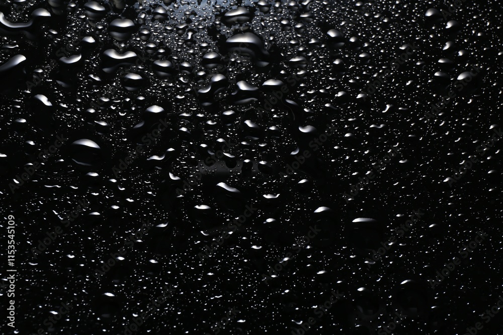 Fototapeta premium Water drops on black glass surface, top view