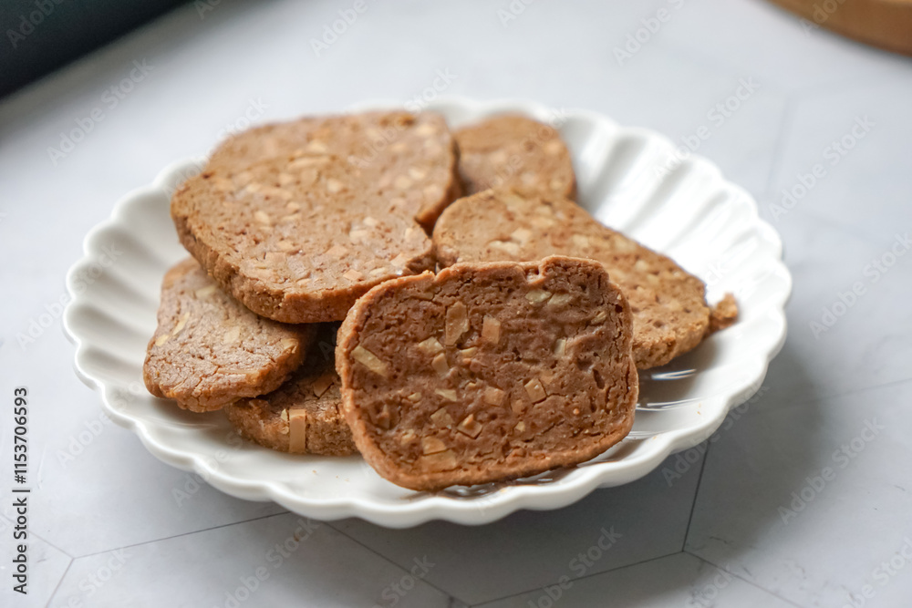 A close-up view of delicious chocolate almond cookies neatly arranged on a white plate. A popular cookies in Malaysia during Eid Mubarak (Hari Raya) A close-up view of delicious chocolate almond cookies neatly arranged on a white plate. A popular cookies in Malaysia during Eid Mubarak (Hari Raya)