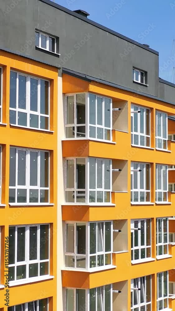 New multi storey in the city. Modern design of apartment building with orange walls with large balconies. Facade of luxury house for city residents. Vertical video New multi storey in the city. Modern design of apartment building with orange walls with large balconies. Facade of luxury house for city residents. Vertical video