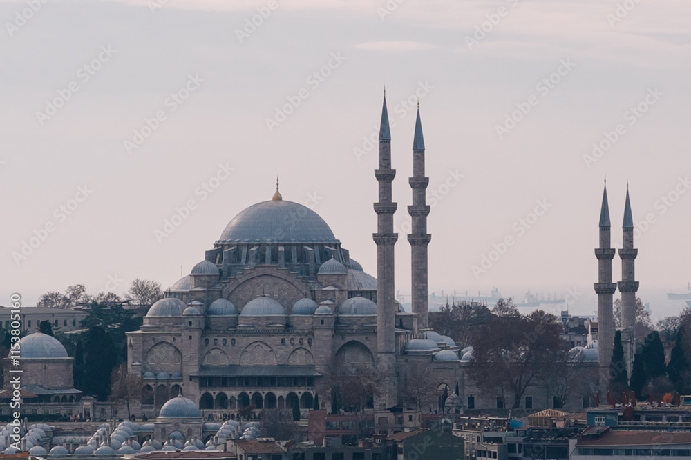 Obraz premium Majestic Suleymaniye Mosque in Istanbul, showcasing Ottoman architecture with its grand domes, towering minarets, and intricate details, with cargo ships in the marmara sea in the background, Turkey