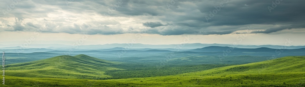 Obraz premium Expansive green hills under a cloudy sky, showcasing natural beauty.