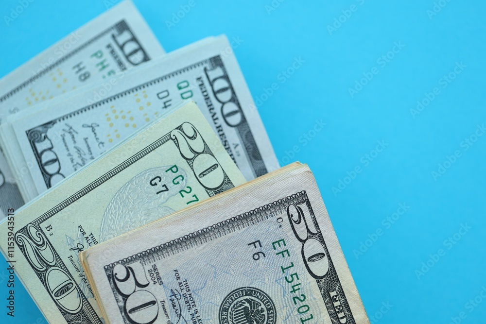 Big amount of hundred, fifty and twenty dollar bills in thick stack lies on bright blue color paper background Big amount of hundred, fifty and twenty dollar bills in thick stack lies on bright blue color paper background