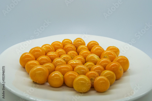 fresh yellow gooseberries on a white plate in front of a white background