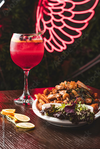 Bild auf Leinwand Plato de chorrillana tradicional con papas fritas y carne junto a un cóctel de frutos rojos en copa de balón