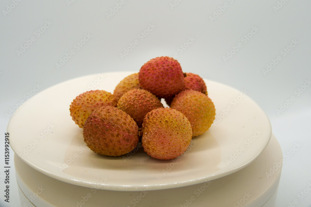 Fresh litchi fruit on a white plate in front of a white background Fresh litchi fruit on a white plate in front of a white background
