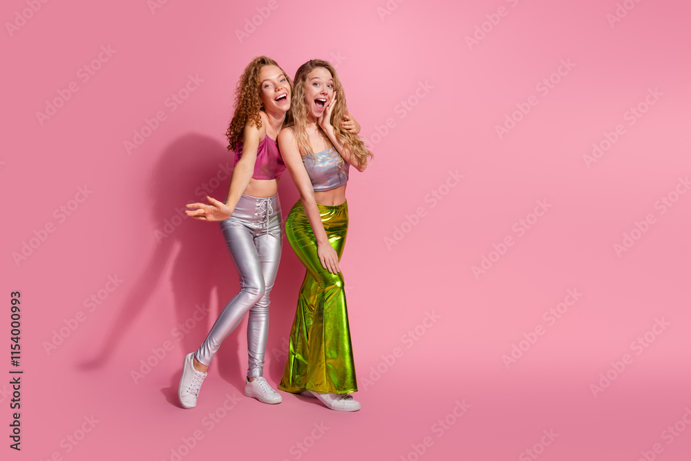 Two joyful young women in stylish retro outfits posing against a vibrant pink backdrop, embodying fun and glamour in celebration mode Two joyful young women in stylish retro outfits posing against a vibrant pink backdrop, embodying fun and glamour in celebration mode