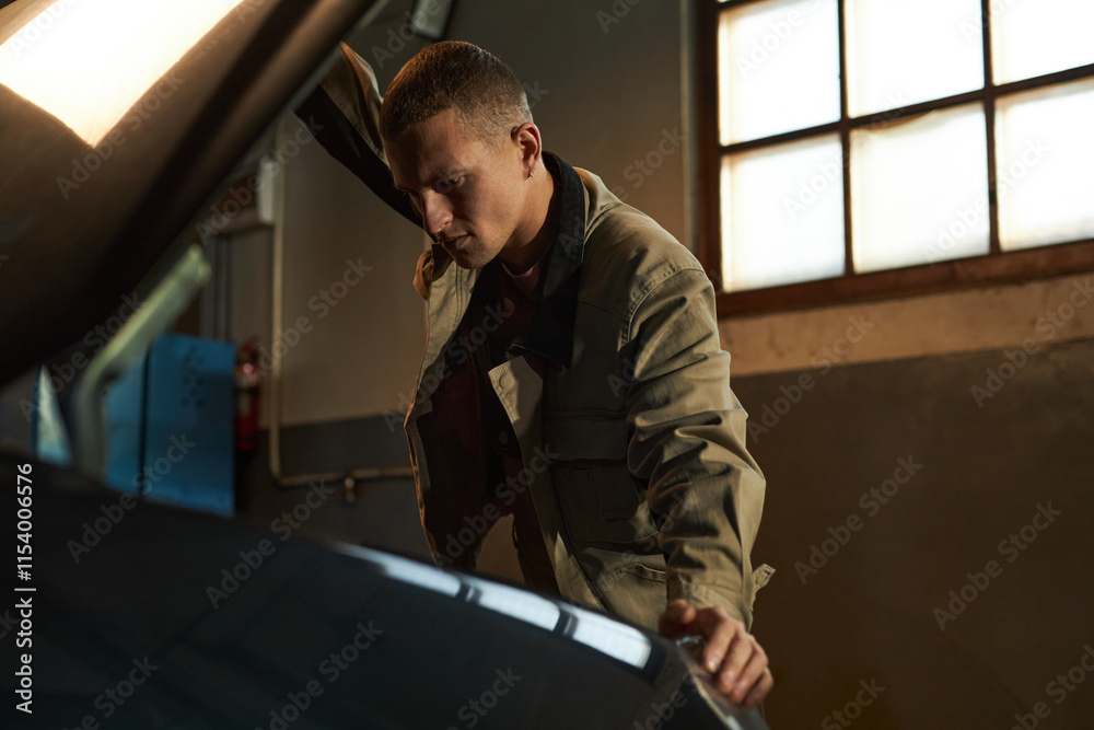 Professional mechanic examining the car in garage Professional mechanic examining the car in garage
