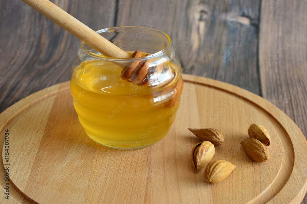 a jar of honey with wooden stick and some nuts on the cutting board a jar of honey with wooden stick and some nuts on the cutting board