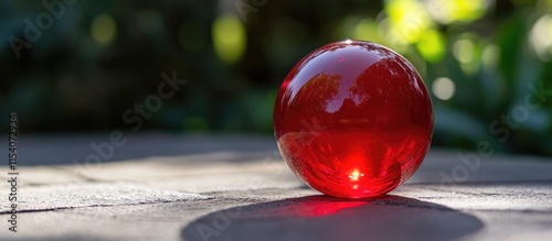 Decorative red glass ball on a stone surface with blurred green background showcasing elegant design and aesthetic charm photo