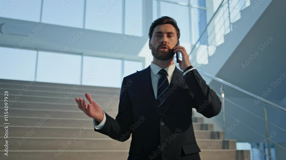 Rich man talking cellphone in modern office building. Confident manager in suit Rich man talking cellphone in modern office building. Confident manager in suit