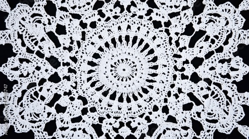 Detailed crochet doily lace background showcasing intricate ornamental patterns in white against a contrasting dark backdrop.