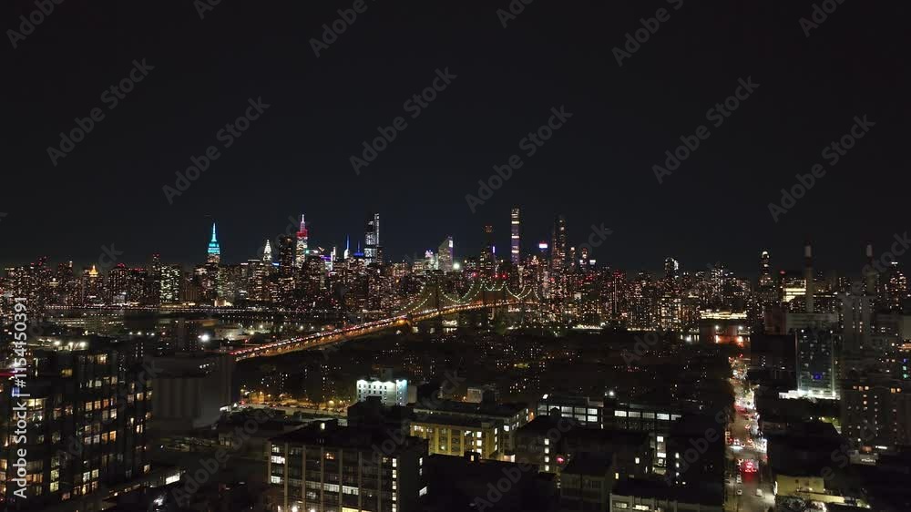 Aerial views capture Queensboro Bridge and Midtown Manhattan skylines at night, with the East River glowing in the foreground, emphasizing the lively cityscape Aerial views capture Queensboro Bridge and Midtown Manhattan skylines at night, with the East River glowing in the foreground, emphasizing the lively cityscape