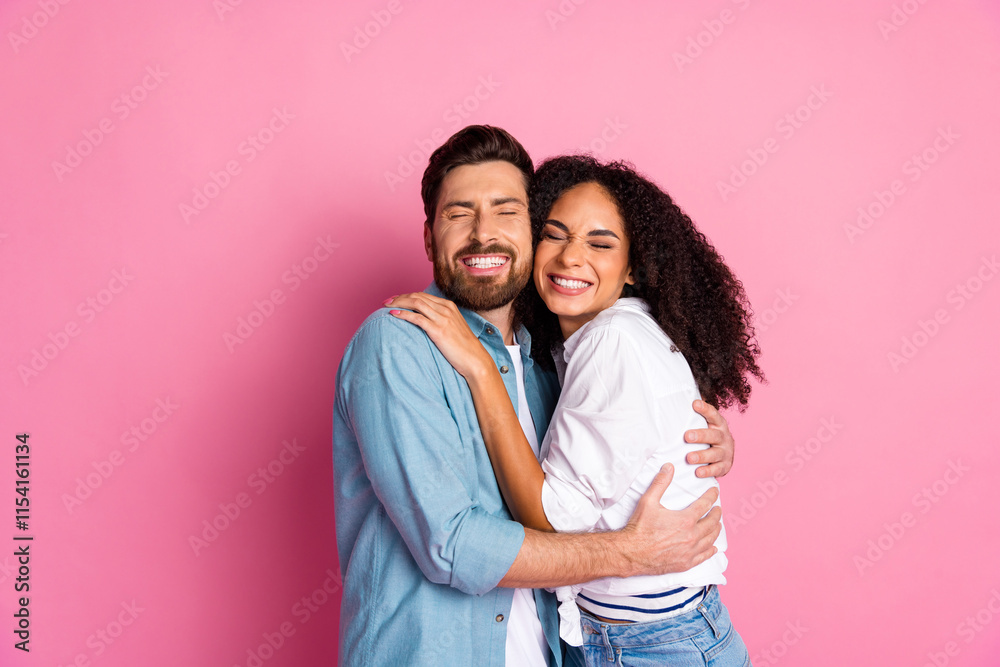 Couple smiling cheerfully while embracing against a vibrant pink background Couple smiling cheerfully while embracing against a vibrant pink background