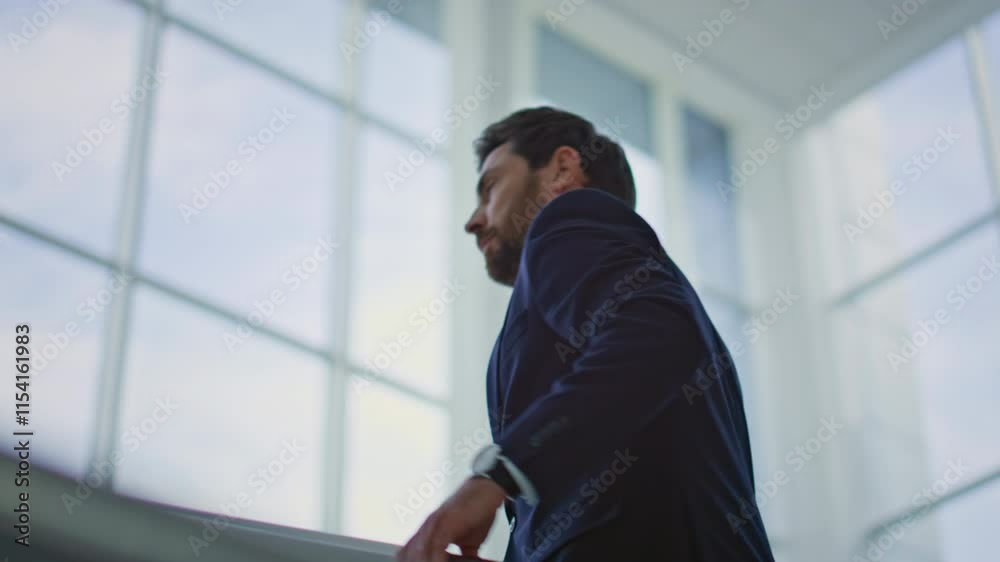 Rich man climbing stairs holding on metal railings. Stylish executive walking Rich man climbing stairs holding on metal railings. Stylish executive walking