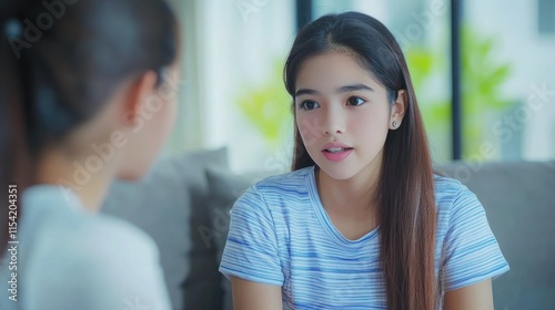 Two young women sit on a couch and share a meaningful conversation in a stylish living room