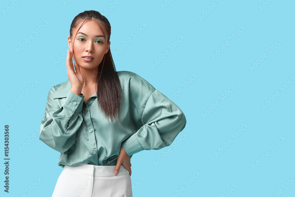 Beautiful young Asian woman with stylish mint makeup on blue background Beautiful young Asian woman with stylish mint makeup on blue background