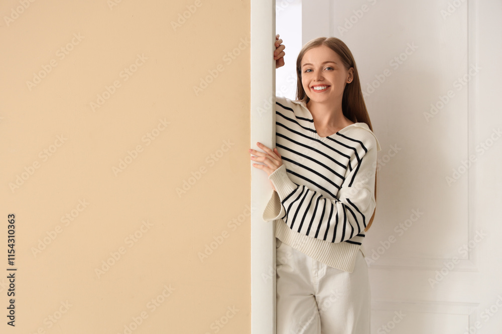 Curious young woman looking out the door at home