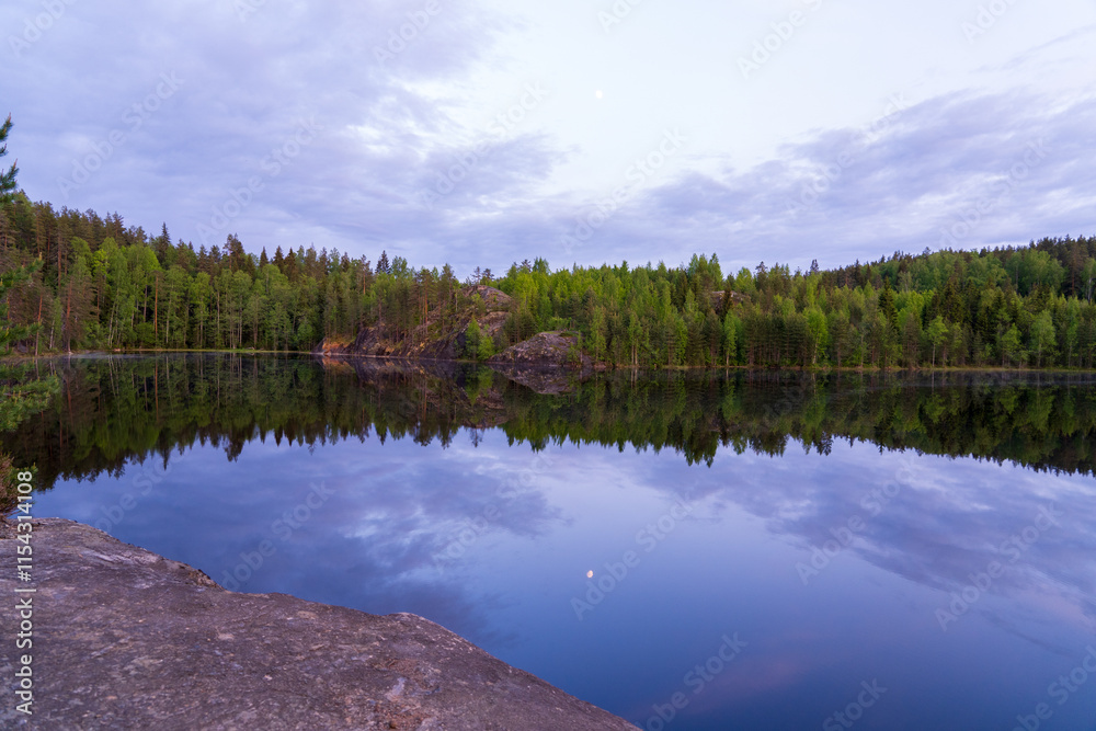 Fototapeta premium A forest lake with water like a mirror reflecting the forest and the sky.