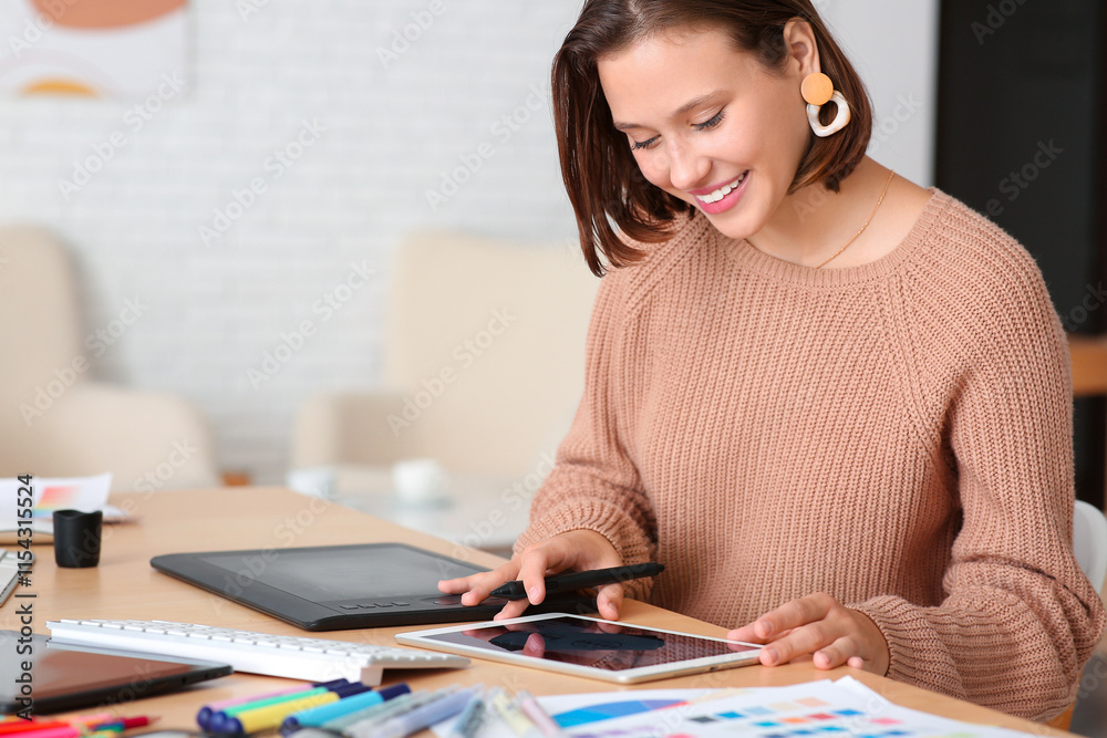 Young female graphic designer working with tablet computer at table in office Young female graphic designer working with tablet computer at table in office