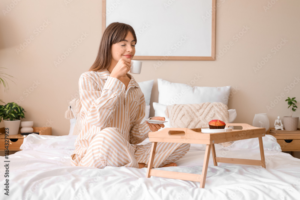 Beautiful young happy woman in pajamas with cup of coffee and cupcake having breakfast at home Beautiful young happy woman in pajamas with cup of coffee and cupcake having breakfast at home