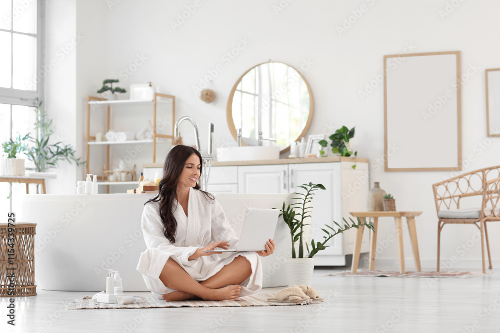 Beautiful young happy woman with laptop and cosmetic products sitting in bathroom Beautiful young happy woman with laptop and cosmetic products sitting in bathroom